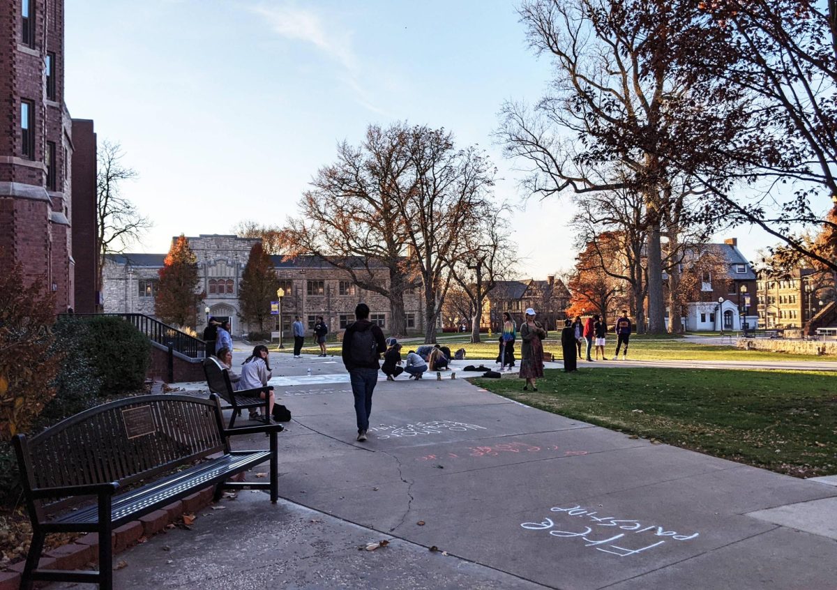 Students drawing Pro-Palistine messages with chalk on the sidewalk outside Seymour Union